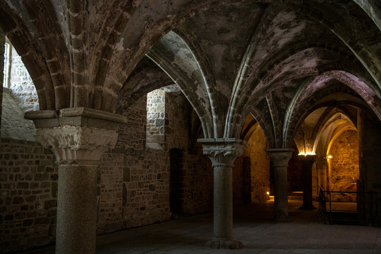 Bóvedas y arcos góticos de una cripta subterránea de piedra, similar a la cripta arqueológica del parvis de Notre-Dame